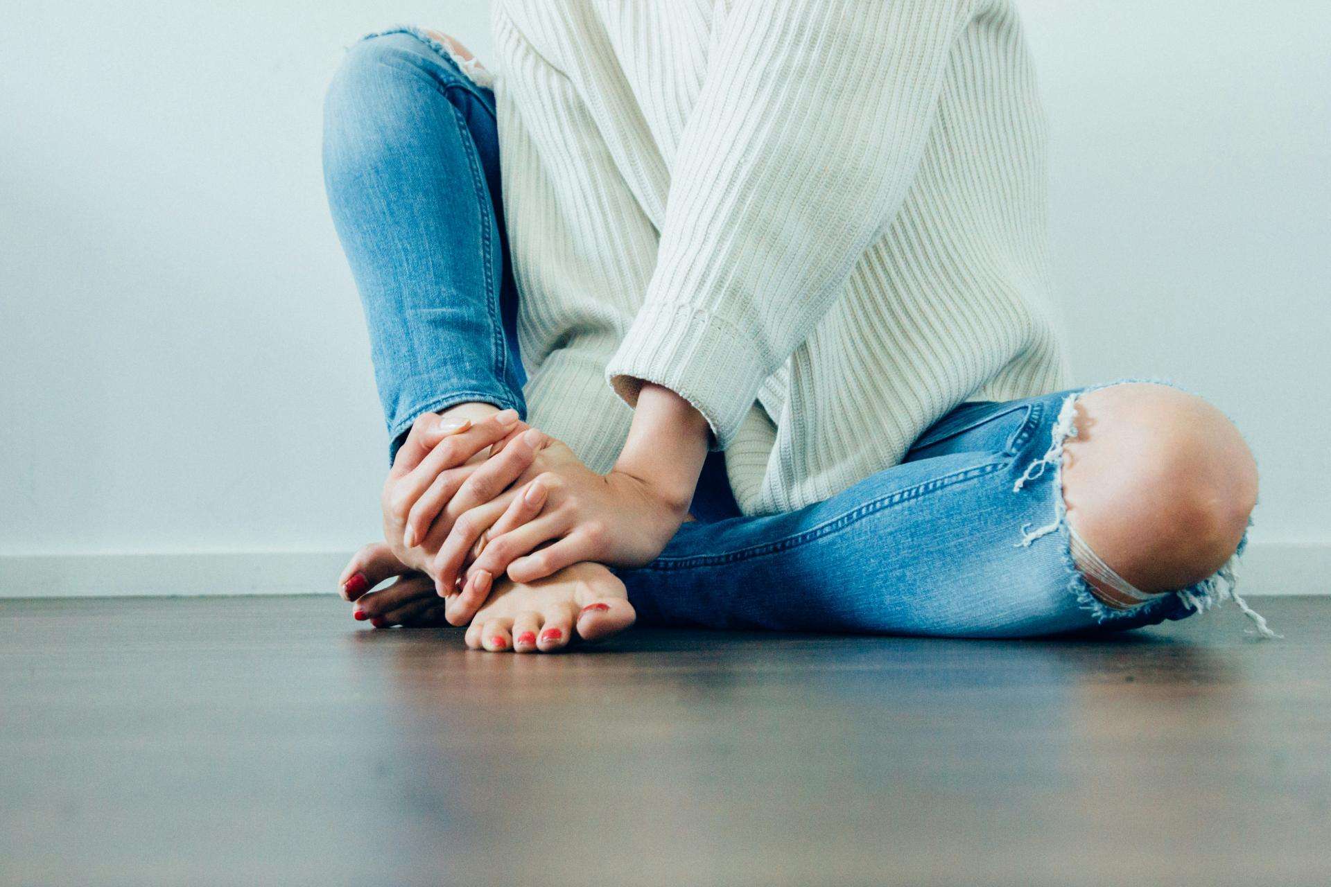 Woman's lower body sitting on the floor, wearing casual clothing, symbolising introspection and self-reflection.